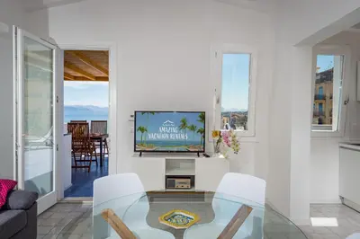 a living room with a tv and a glass table at Terrazza BluOltremare, Castellammare del Golfo in Castellammare del Golfo