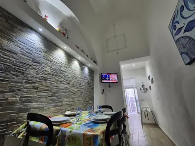 a dining room with a table and a stone wall at Ad 1 passo dal mare Mondello in Palermo