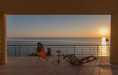 a balcony with a view of the ocean at sunset at Seaside Villa Capo Zafferano in Bagheria