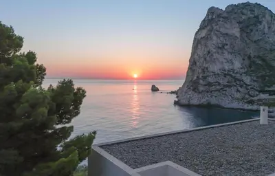 a sunset over the ocean with a rock formation at Seaside Villa Capo Zafferano in Bagheria