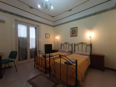a bedroom with two beds and a desk and a window at Casa Mille in Palermo