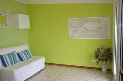 a green room with a couch and a vase of flowers at B&B Talìa in Scopello