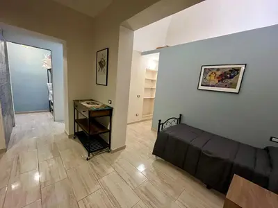 a living room with a bed and a hallway at Donna Maria in Cinisi