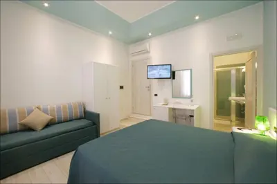 a room with a bed and a couch and a television at Accussì rooms in San Vito lo Capo