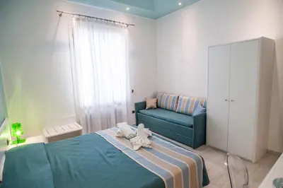 a bedroom with a blue bed and a couch at Accussì rooms in San Vito lo Capo