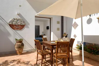 a dining room with a table and chairs and an umbrella at Le Margherite in San Vito lo Capo