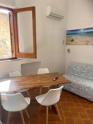 a living room with a wooden table and white chairs at nanzi u mare in San Vito lo Capo