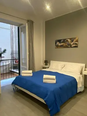 a bedroom with a bed with blue sheets and a balcony at CASE VACANZE FraEmily , PALERMO in Palermo
