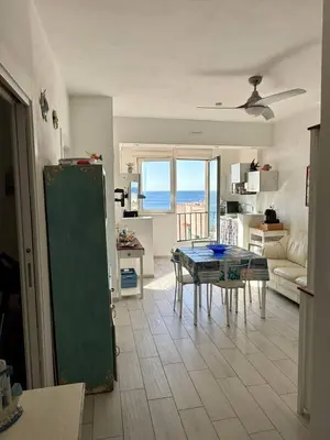 a kitchen and living room with a table and a couch at Sea Pearl House in Isola delle Femmine