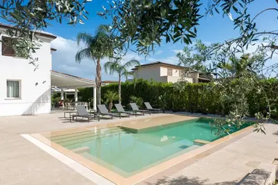 a swimming pool in a yard with chairs and a house at Villa Dafni Private Pool & Relax near Cefalù in Campofelice di Roccella