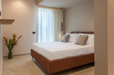 a bedroom with a bed with white sheets and a window at Villa Dafni Private Pool & Relax near Cefalù in Campofelice di Roccella