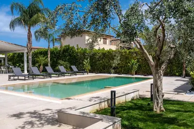 a swimming pool with lounge chairs and a tree at Villa Dafni Private Pool & Relax near Cefalù in Campofelice di Roccella