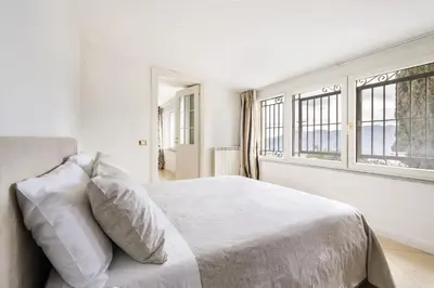 a white bedroom with a bed and two windows at Villa Bouganville in Monreale