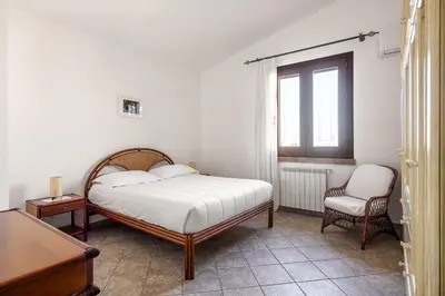 a bedroom with a bed and a chair and a window at Villa Zagara Swimming Pool and Seaview in Ficarazzi