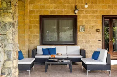 a patio with a couch and two chairs and a table at Villa Zagara Swimming Pool and Seaview in Ficarazzi