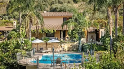 a house with a swimming pool and palm trees at Villa Zagara Swimming Pool and Seaview in Ficarazzi