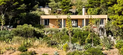 a house on the side of a hill with trees at villa Capo Zafferano in Bagheria