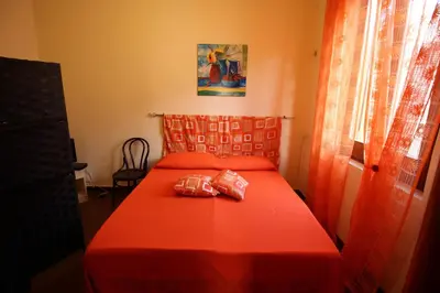 a bedroom with a red bed with a pillow on it at Bovio guest House in Castellammare del Golfo