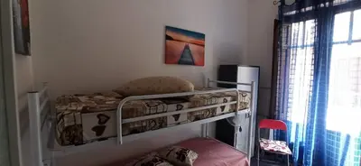 a small bedroom with a bunk bed with a chair at Bovio guest House in Castellammare del Golfo