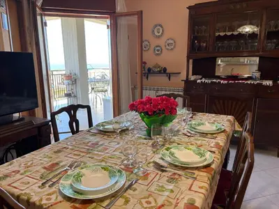 a table with plates and a vase of flowers on it at Appartamento Vista Golfo in Castellammare del Golfo