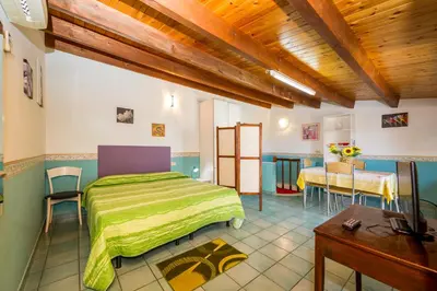 a bedroom with a green bed and a table at Appartamento vista mare in Castellammare del Golfo