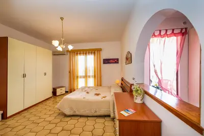 a bedroom with a bed and a table and a window at Appartamento vista mare in Castellammare del Golfo
