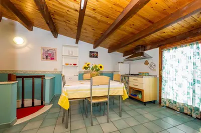 a dining room with a table and a kitchen at Appartamento vista mare in Castellammare del Golfo