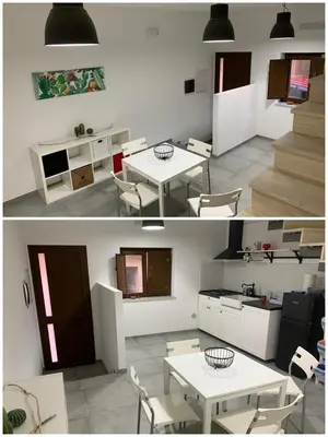 a living room with a white table and a kitchen at Dai Mori in Lascari