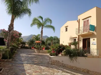 a resort with palm trees and a building at Le Falesie di Castelluzzo in Castelluzzo