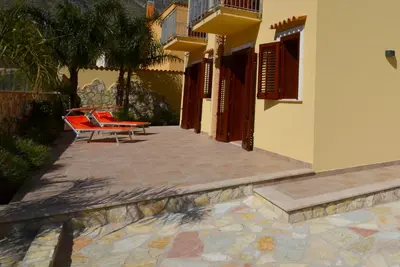a patio with two chairs and a building at Le Falesie di Castelluzzo in Castelluzzo