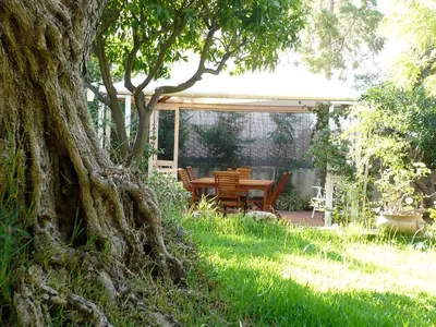 a table and chairs in a garden with a tree at Villa Soliva - Mare e Panorama Unico in Mondello