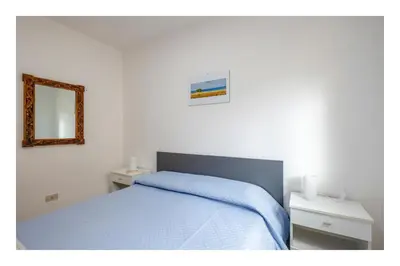 a bedroom with a blue bed and a mirror at Battigia SOLEMAR-Alcamo Marina in Alcamo Marina