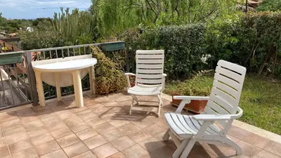 two white chairs and a table on a patio at Scopello Beach in Scopello