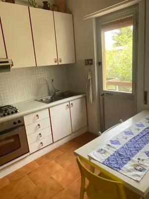 a kitchen with white cabinets and a table and a window at Scopello Beach in Scopello