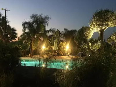 a swimming pool at night with palm trees and lights at Villa with private pool and wonderful view in Carini