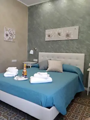 a bedroom with a blue bed with towels on it at Anninedda Rooms in Palermo