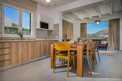 a kitchen and dining room with a wooden table and yellow chairs at VILLA AGLEA Luxury By Sicily Home Solutions in Castellammare del Golfo