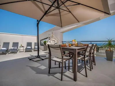 a dining table with chairs and an umbrella on a patio at Apartment Attico Dolce Vista by Interhome in Castellammare del Golfo