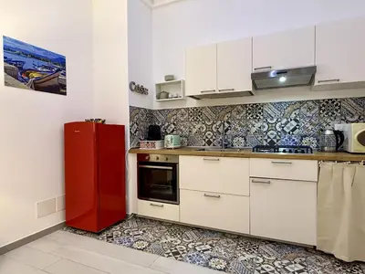 a kitchen with white cabinets and a red refrigerator at Casa Bellini in Palermo
