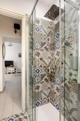 a glass shower in a room with a wall of tiles at Casa Bellini in Palermo