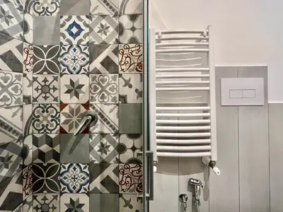 a bathroom with a shower and a tile wall at Casa Bellini in Palermo