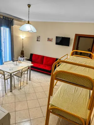a living room with a red couch and tables and chairs at Onda Blu Apartment in Balestrate