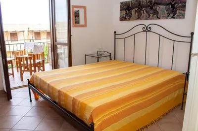 a bedroom with a bed in a room with a balcony at euforbia in San Vito lo Capo