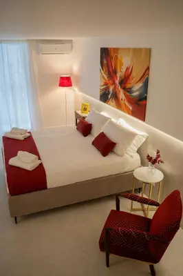 a bedroom with a large bed and a red chair at Dimora Ballarò in Palermo