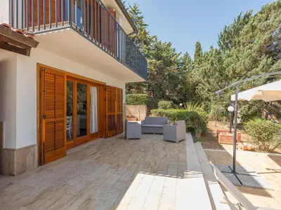 a patio with chairs and an umbrella next to a house at Villa Hybiscus con piscina in Castellammare del Golfo