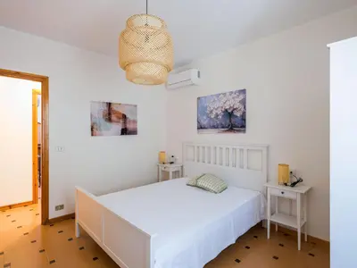 a white bedroom with a bed and two tables at Villa Hybiscus con piscina in Castellammare del Golfo