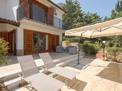 a patio with two chairs and an umbrella at Villa Hybiscus con piscina in Castellammare del Golfo