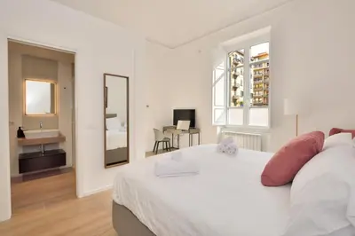 a white bedroom with a large bed and a bathroom at Palazzo Gregorietti Boutique Apartments in Palermo