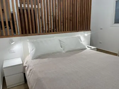 a bedroom with a white bed with a wooden headboard at A Casa di Chiara in Palermo