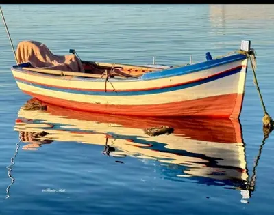 a boat sitting on the water with its reflection at Carruzzata 2 in Bagheria